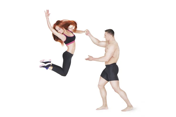 Entrenador de fitness sostiene a la chica deportiva en salto de la mano — Foto de Stock