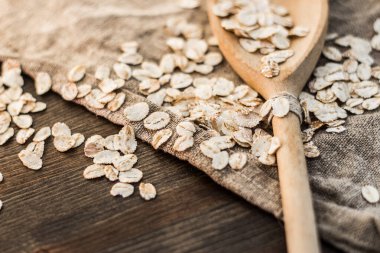 Ahşap arka planda dağınık yulaf ezmesi ve kaşık