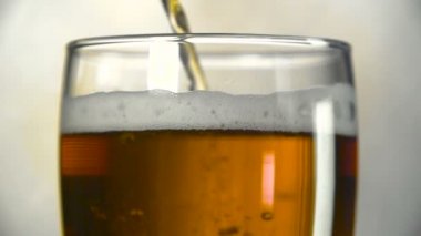 Karanlık bira bir cam içine dökülür. Ağır çekim bira kabarcıkları.