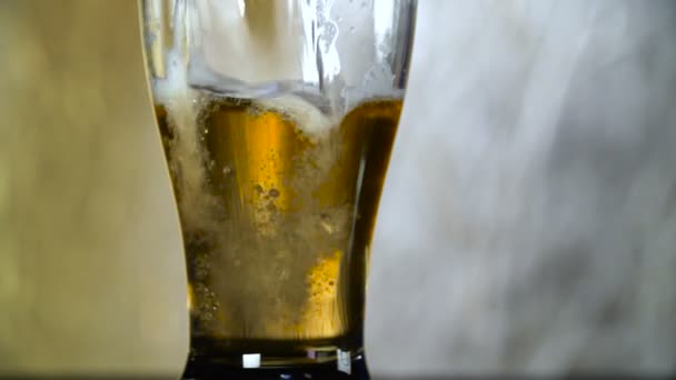 Light bier wordt gegoten in een glas op een grijze achtergrond — Stockvideo