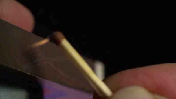 Le match en main se déplace du côté de la boîte d'allumettes et s'allume. Macro. Gros plan. Profondeur de champ faible 