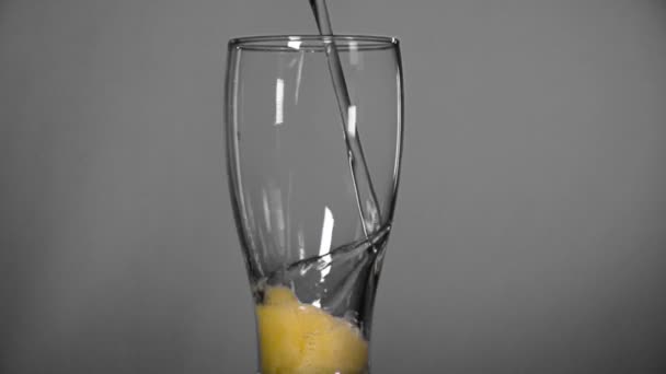 La cerveza se vierte en un vaso transparente sobre un fondo gris — Vídeos de Stock