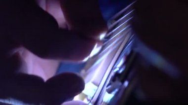Bir adam bir elektro gitar çalar. El ve dizeleri - kadar karanlık bir odada kapatın. Ağır çekim.