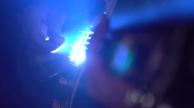 Bir adam bir elektro gitar çalar. Elimi parlak ışık. Ağır çekim.