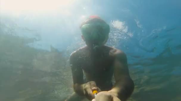 Een jonge man in een masker zwemmen met een buis wordt ondergedompeld onder water. Ze zwaait haar hand. De pret van de zomer, watersporten. Kust van de Zwarte Zee. Go-Pro videocamera. — Stockvideo