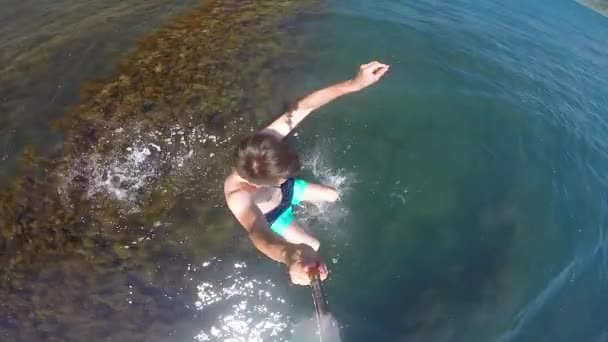 A young man on the shore of the Black Sea in a swimming mask with a tube jumps submerges under the water. — Stock Video