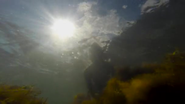 A young man with a swimming mask waving a pipe under water waves his hand. Summer fun, water sports. Coast of the Black Sea. — Stock Video