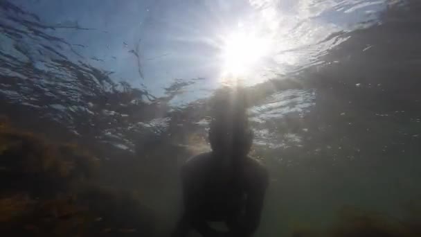 Un giovane uomo con una maschera da nuoto che agita un tubo sott'acqua ondeggia la mano. Divertimento estivo, sport acquatici. Costa del Mar Nero . — Video Stock