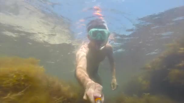 Een jonge man in een masker zwemmen met een buis wordt ondergedompeld onder water. Ze zwaait haar hand. De pret van de zomer, watersporten. Kust van de Zwarte Zee. Go-Pro videocamera. — Stockvideo