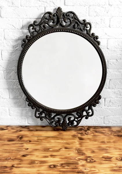 Empty mirror in the interior. Mock up with vintage circle frame. White brick wall and wooden table on background.