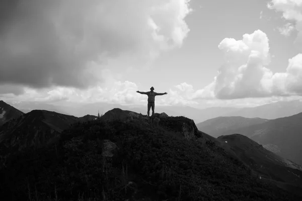 Man with open arms on the top of the mountain.