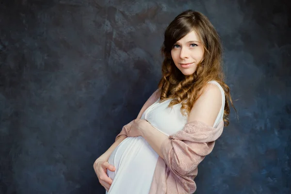 Expectant mother on dark background. Maternity fashion, femininity, pregnancy concept.