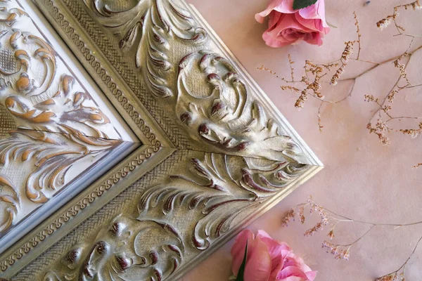 Corners of decorative picture frames and flowers on pastel pink backdrop.