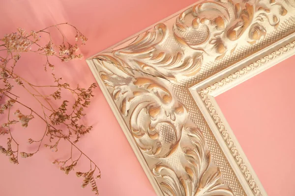 Corner of empty decorative picture frame on pink background.