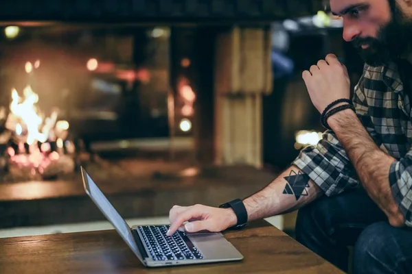 Stilig skäggig man använder mobil bärbar dator medan de vilar i lobbyn hotel. Man använder elektroniska gadget. Suddig bakgrund. Nödraketer, bokeh — Stockfoto