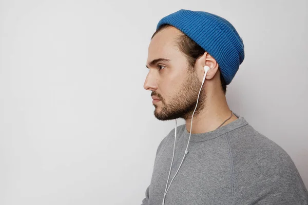 Pohledný mladý muž poslechu hudby ve sluchátkách prázdné světlo prázdné pozadí v ateliéru. Horizontální. — Stock fotografie