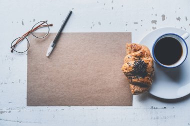 Mockup boş tekne sayfası boş kağıt, kalem, gözlükleri ve sabah kahve Kupası Beyaz ahşap masa üzerinde kruvasan ile. İş geçmişi mektup yazmak için. Yaratıcı çalışma kavramı.