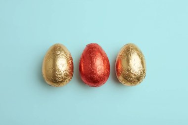 Oda veya kopyalama, metin, sözcükler için alan ile mavi arka plan üzerinde renkli Paskalya yumurtaları renkli folyo üst taraftan görüntüleyin. Yatay.