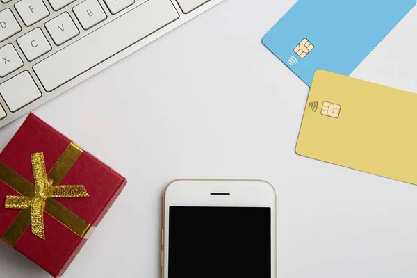 Makett két üres színes hitelkártyát, smartphone, üres, fehér íróasztal ajándék doboz. Üzleti modell háttérben üzenet írása. Felülnézet. Vízszintes. — Stock Fotó