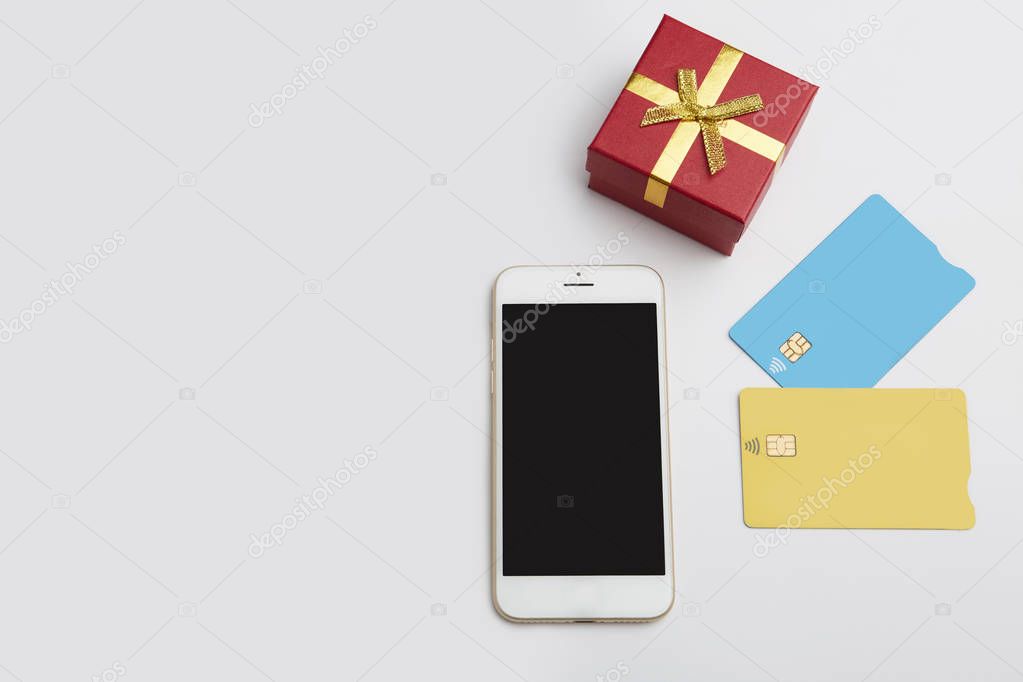 Mockup of two blank color credit cards, smartphone, gift box on empty clear desk. Business mock-up background for message writing.Top view. Horizontal.