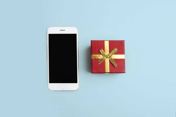 Makett smartphone, ajándék doboz üres kék tiszta asztalon. Üzleti modell háttérben üzenet írása. Felülnézet. Vízszintes. — Stock Fotó