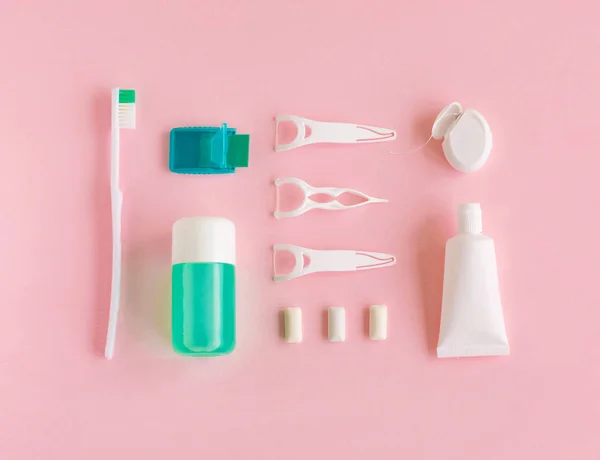 Cepillos de dientes, pasta de dientes, enjuague y goma de mascar engastados sobre fondo rosa . — Foto de Stock
