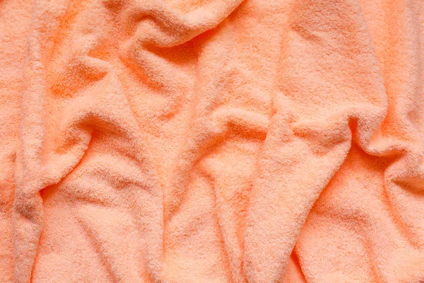 Soft peach fabric with waves and folds. Soft pastel textile texture.