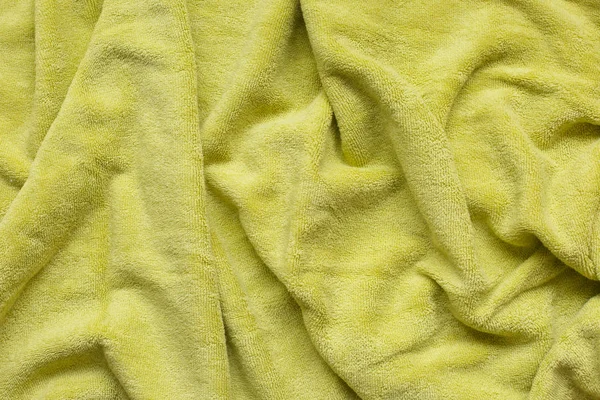 Soft green fabric with waves and folds. Soft textile texture.