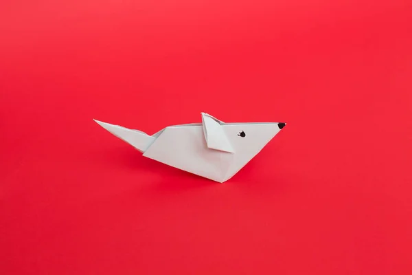 Origami ratón de papel blanco sobre fondo rojo . — Foto de Stock