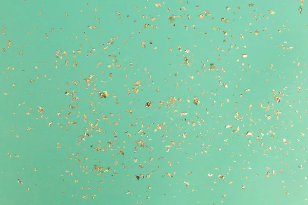 Caída de confeti de oro sobre fondo de menta. Concepto simple vacaciones —  Fotos de Stock