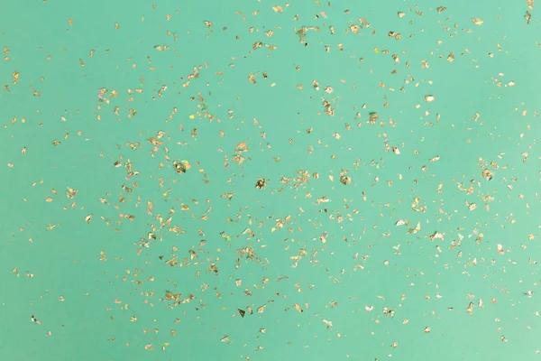 Um confete dourado em pano de fundo de menta. Conceito de férias simples — Fotografia de Stock