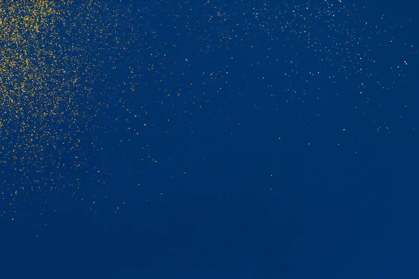 Textura de brilho dourado sobre um fundo azul. Elemento de design. Explosão de ouro de confete . — Fotografia de Stock