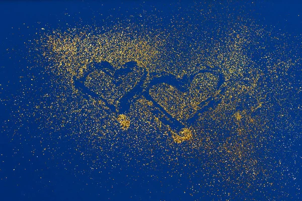 Dos corazones hechos de brillo dorado sobre fondo de tendencia azul . — Foto de Stock