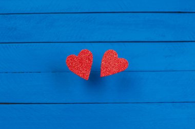Mavi ahşap arka planda iki kırmızı kalp, yakın plan,