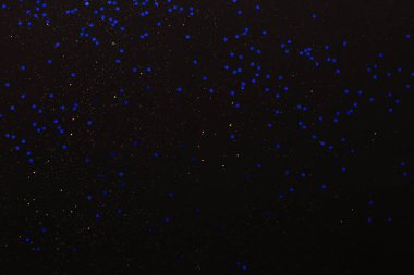 Siyah arka planda altın parıltısı ve mavi yıldızlar. Tatil soyut dokusu