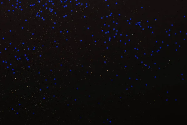 Gold glitter and blue stars on black background. Holiday abstract texture