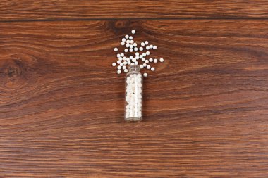 Bottle with homeopathic pills on wooden background.