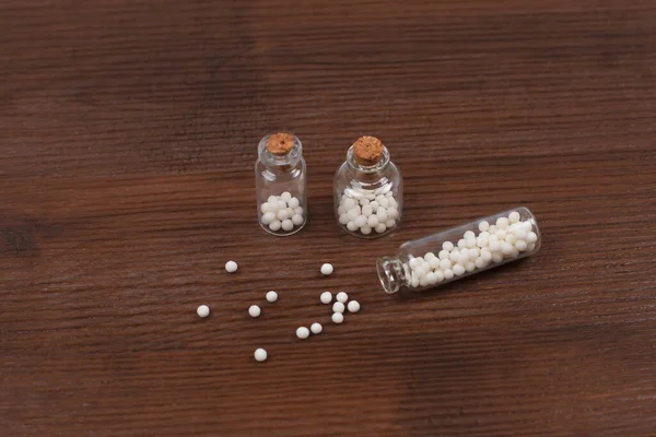Homeopatické koule a tři skleněné láhve na dřevěném pozadí — Stock fotografie