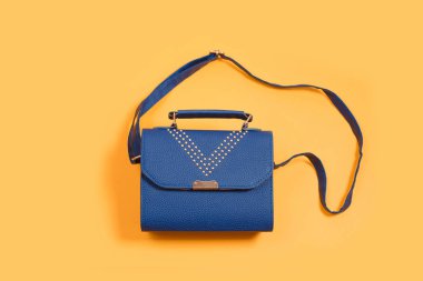 Kadın deri küçük el çantası sarı arka planda. Kadın şeylerinde minimalizm. Renk eğilimi 2020 mavi.