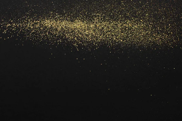 Gold glitter on black background. Design element. Golden grainy abstract texture on a black background. Holiday background