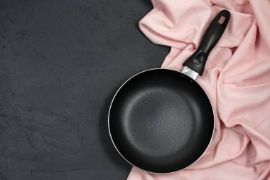 Siyah masasında pembe mutfak havlusu olan boş bir tava. Üst Manzara. Boşluğu kopyala.