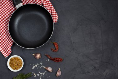 Yemek pişirme arka planında siyah tava ya da tava, baharatlar ve siyah arka planda otlar. Üst Manzara. Boşluğu kopyala