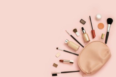 Hafif arka planda pembe kozmetik çantadan dekoratif kozmetik seti. Metnin için metin boşluğu. Üst manzara, düz uzanma.