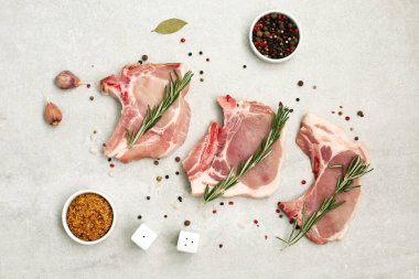 Hafif arka planda çiğ biftek. Çiğ domuz bifteği, otlar ve baharatlar. Et pişiriyorum. Üst görünüm