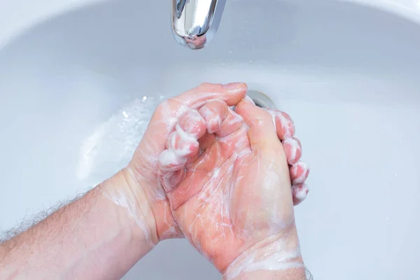 A Man is washing his hands with soap in bathroom. Man's hand close up. Hand disinfection and treatment for coronavirus. Quarantine rules. Personal hygiene