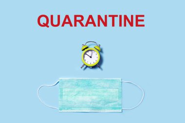 Kelime QuaranTINE, mavi arka planda tek kullanımlık maske ve saat. Düz yat ve uzayı kopyala. Koronavirüs karantinası kavramı.