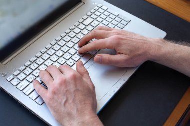 Adamın elleri dizüstü bilgisayarda klavyede daktilo kullanıyor. Seçici odaklanma. Uzaklık öğrenme çevrimiçi eğitim ve çalışma.