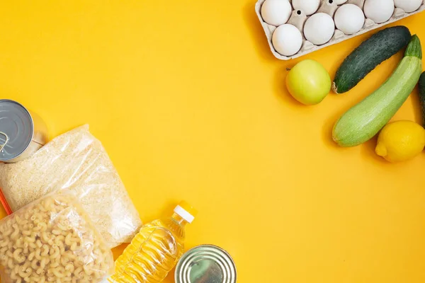 Food donations or food delivery concept on yellow background, top view. Copy space. Humanitarian assistance during the coronavirus pandemic.