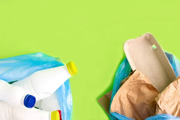 Geri dönüşüm için çöp seçimi. Yeşil arkaplanda plastik ve kağıt