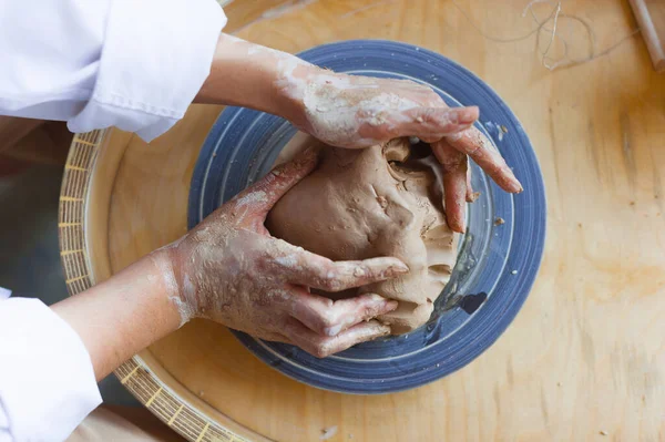 Female potter works with clay, craftsman hands close up, kneads and moistens the clay before work.